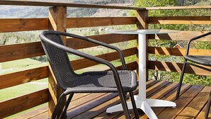 A wooden deck with two wicker chairs and a glass table, overlooking a mountainous landscape. - 10 Person Holiday Home in Bygstad (Sunnfjord)