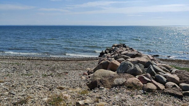 Une côte rocheuse offrant une vue dégagée sur la mer et sur l’horizon lointain.