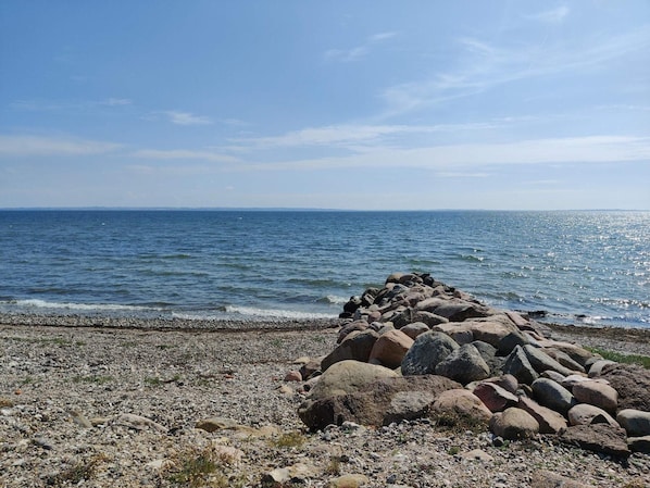 En stenig kustlinje med fri sikt  över havet och en avlägsen horisont.