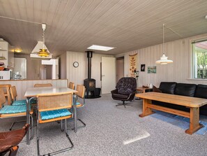 Un espace de vie compact comprenant un coin cuisine, un espace repas avec une table et des chaises, un canapé et une grande fenêtre laissant entrer la lumière naturelle.