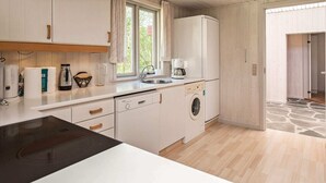 Une cuisine compacte avec des meubles blancs, un four encastré, un lave-linge et une machine à café.