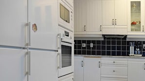A kitchen with white cabinets, a built-in oven, a microwave, and a coffee maker. - Holiday Home in Skärhamn (Skaerhamn)