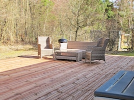 A wooden deck with wicker furniture including a sofa and two chairs.