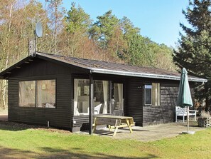 A small cabin with a porch, a bench, and an umbrella. - Tranquil Holiday Home in Hals near Beach (Hals)