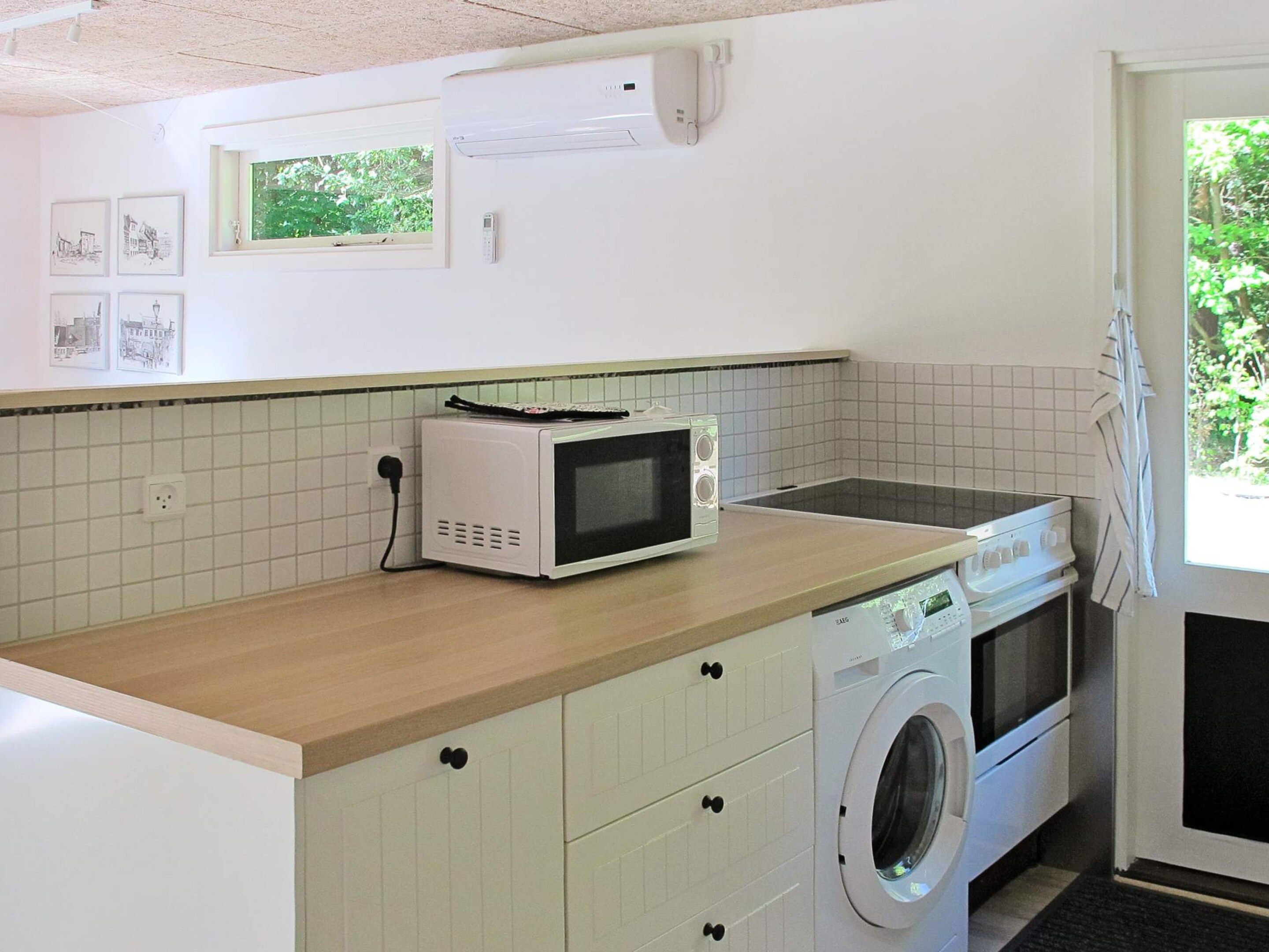 Cocina pequeña equipada con microondas, estufa y lavadora.