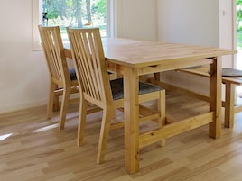 A wooden dining table with chairs in a room with wooden flooring and a window.