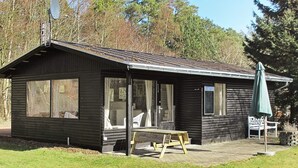 A small cabin with a porch, a picnic table, and an umbrella. - Tranquil Holiday Home in Hals near Beach (Hals)