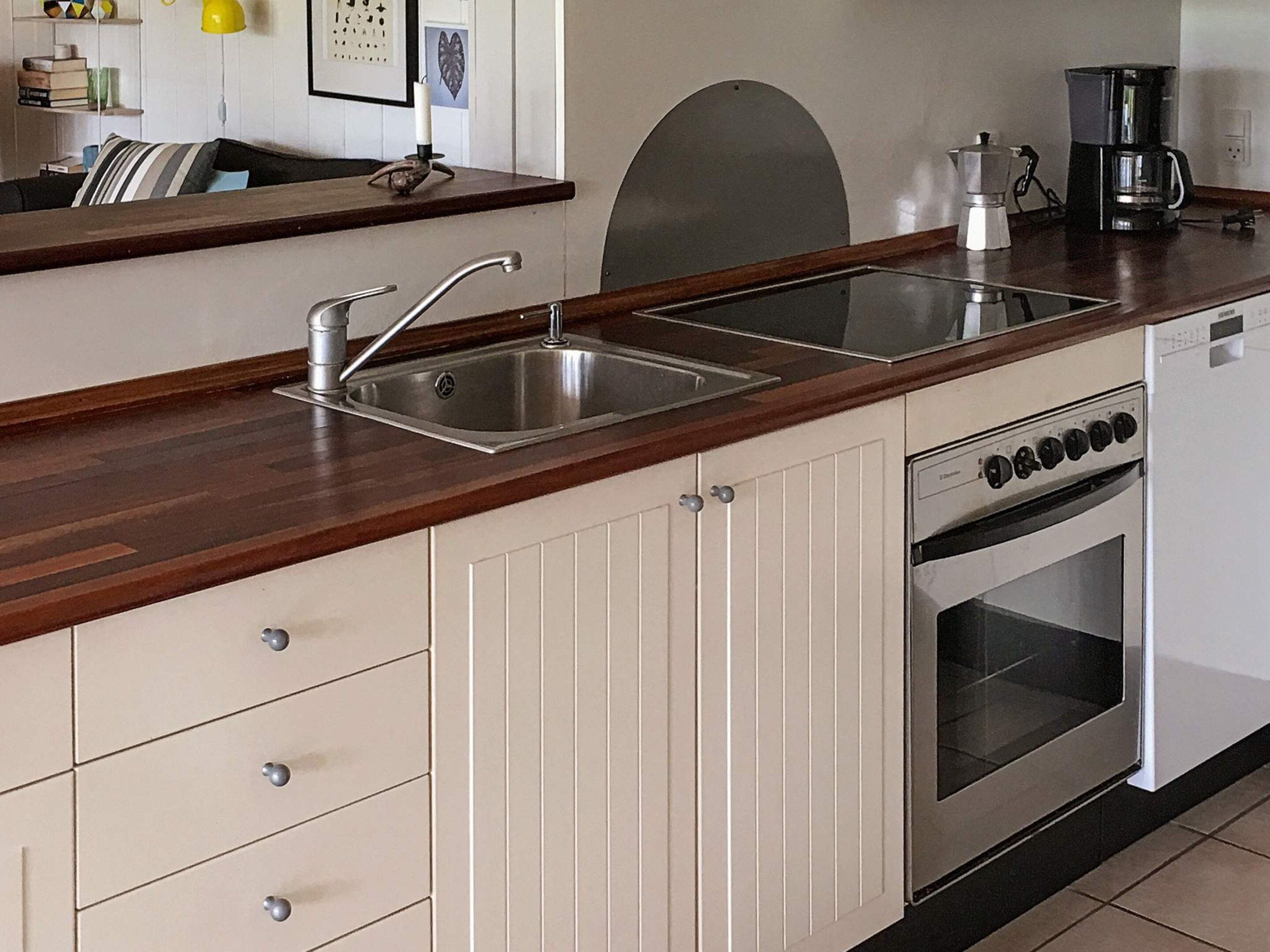 A kitchen with a double sink, a coffee maker, and a stove.