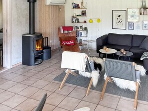 A cozy living room with a fireplace, a sofa, two armchairs, and a small table. - 5 Star Holiday Home in Dannemare (Dannemare)
