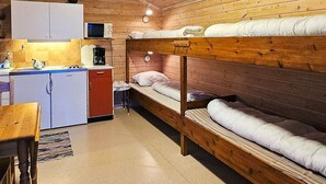 En stuga med våningssängar, ett litet kök, ett matbord och en liten köksdel.