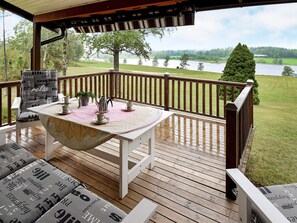 A wooden deck with a table set for two, overlooking a lake.