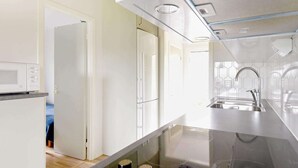 Une cuisine moderne équipée d’un four à micro-ondes, d’un évier en acier inoxydable et d’un îlot central avec un plan de travail en verre.