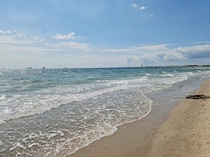 A beach with waves lapping onto the shore, a clear sky, and distant ships. - Quaint Holiday Home in Skagen near Sea (Skagen)