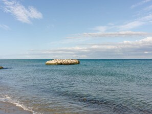 Un mar tranquilo con un promontorio rocoso a lo lejos.