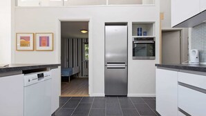A modern kitchen with a built-in dishwasher, a stainless steel refrigerator, and a microwave. There is a small dining area visible through an open door. - 6 Person Holiday Home in Nykobing Sj-by Traum (Nykobing Sjaelland)