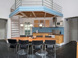 A modern kitchen with a central island, black chairs, and a mezzanine level with a railing. - 4 Star Holiday Home in Ebeltoft (Ebeltoft)