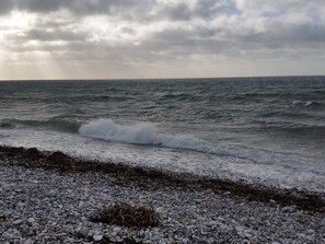 A rocky shoreline with waves crashing onto the pebbles. - 4 Star Holiday Home in Ebeltoft (Ebeltoft)
