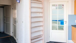 A white door with a glass panel, a wooden ladder leaning against the wall, and a blue object inside. - 4 Star Holiday Home in Ebeltoft (Ebeltoft)