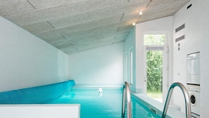 A swimming pool with a blue slide, a white wall with a window, and a built-in washing machine. - 4 Star Holiday Home in Ebeltoft (Ebeltoft)