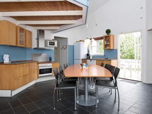 A modern kitchen with wooden cabinets, a central island, and a dining area with chairs. - 4 Star Holiday Home in Ebeltoft (Ebeltoft)