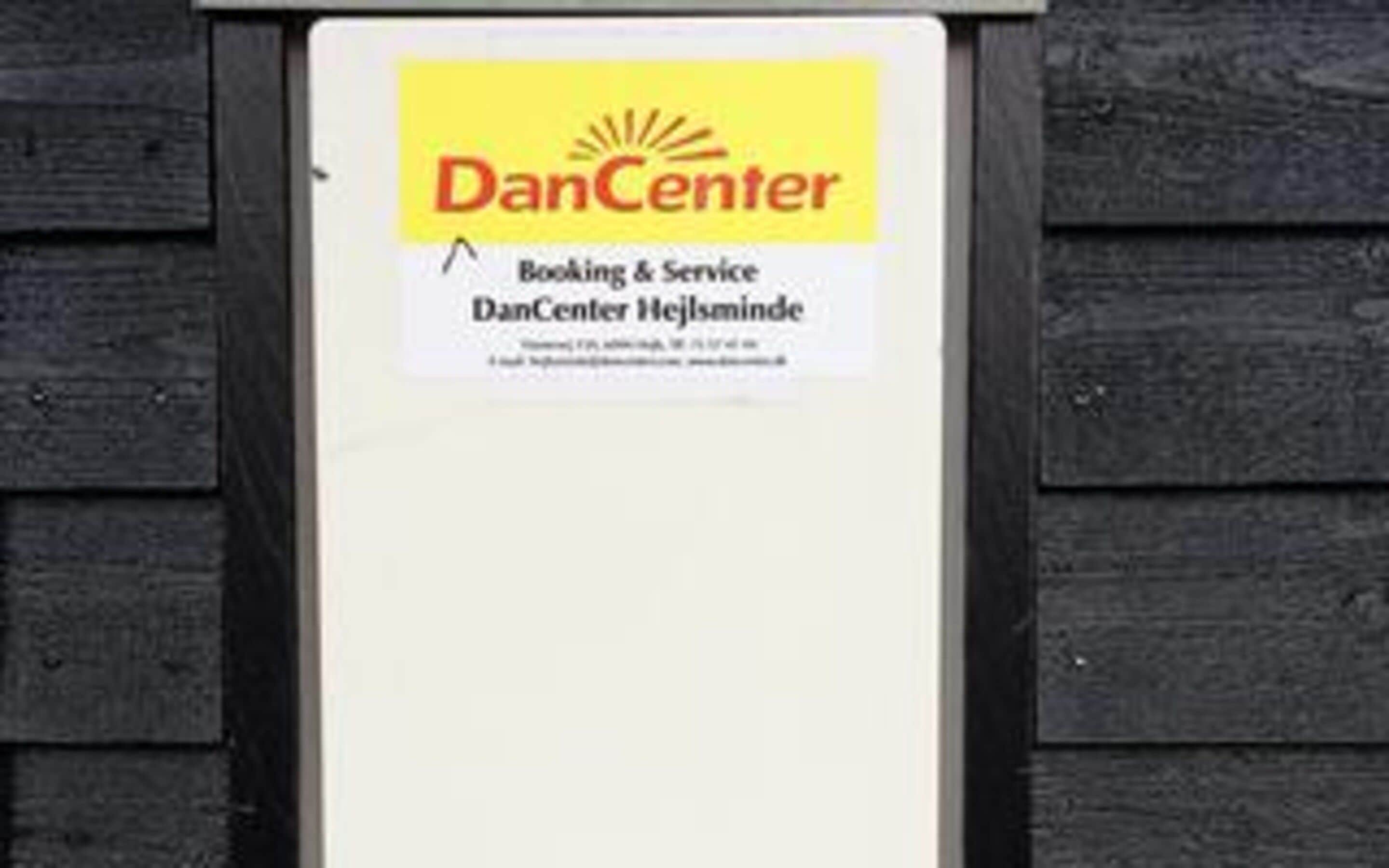A sign with the text 'DanCenter Booking & Service' and 'DanCenter Hejlsminde' on a wooden background.