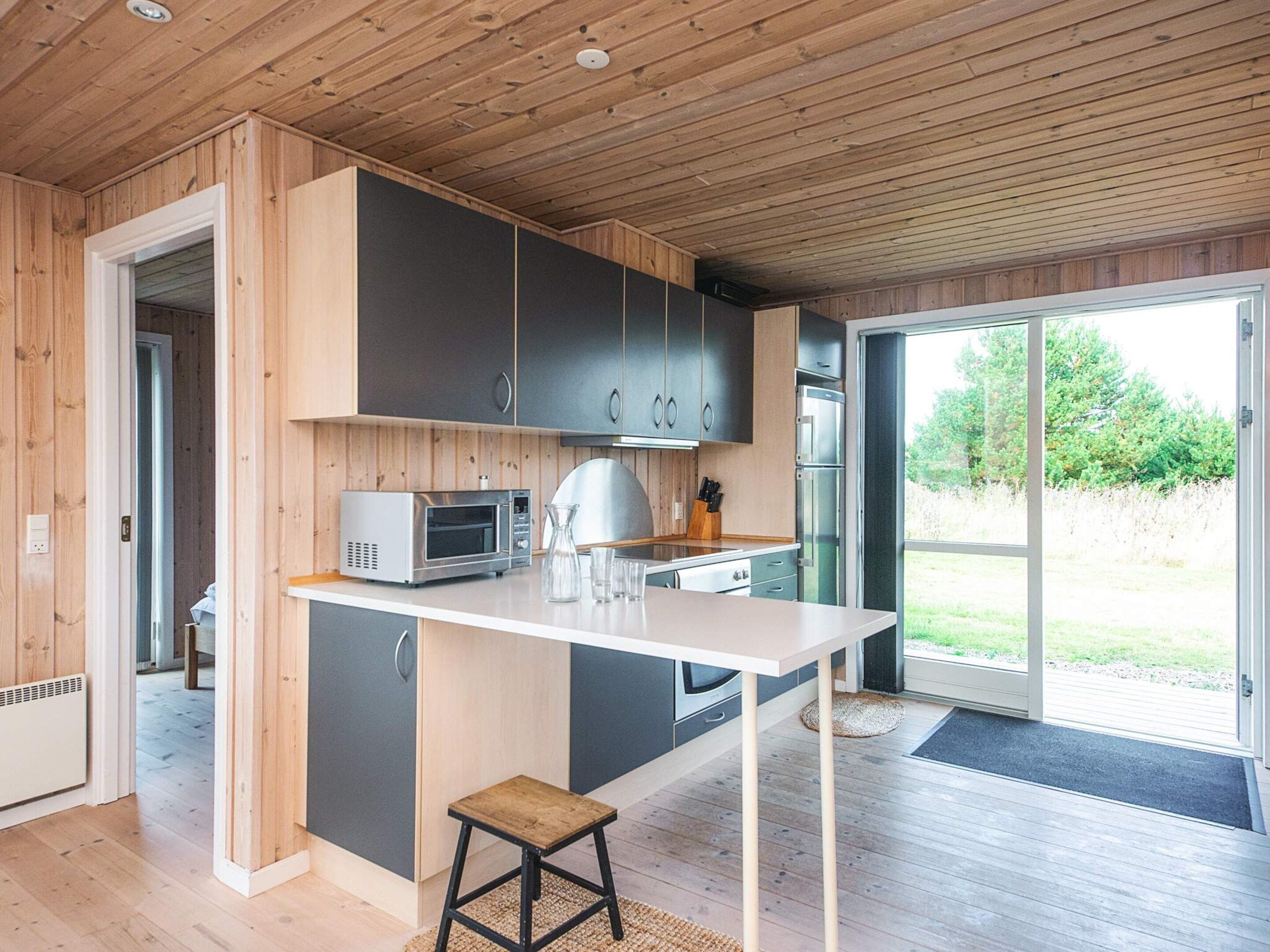 A modern kitchen with a built-in microwave, a large island, and a sliding glass door to the outdoors.