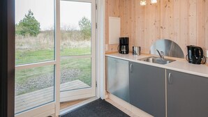 Una cocina moderna con un amplio ventanal corredera que da a un área verde exterior.
