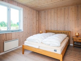 Et værelse med en træseng, et vindue og et sengebord med en lampe.