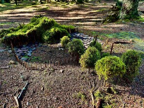 A forested area with a stone pathway, small trees, and moss-covered ground. - Cozy Holiday Home in Ulfborg near Sea (Ulfborg)