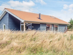A single-story house with a sloped roof and a chimney, surrounded by tall grass. - Cozy Holiday Home in Ulfborg near Sea (Ulfborg)