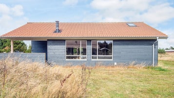 A single-story house with a red-tiled roof, a chimney, and a large window.
