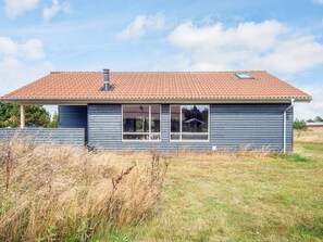 A single-story house with a red-tiled roof, a chimney, and a large window. - Cozy Holiday Home in Ulfborg near Sea (Ulfborg)