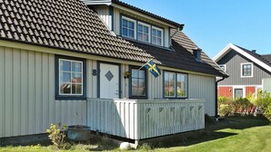 A two-story house with a dark tiled roof, white exterior walls, and a small porch. - Holiday Home in Lysekil (Lysekil)