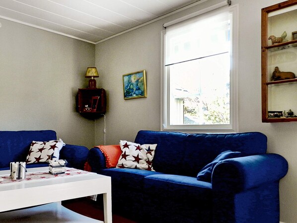 A living room with a blue sofa, a white coffee table, a lamp, and a painting on the wall.