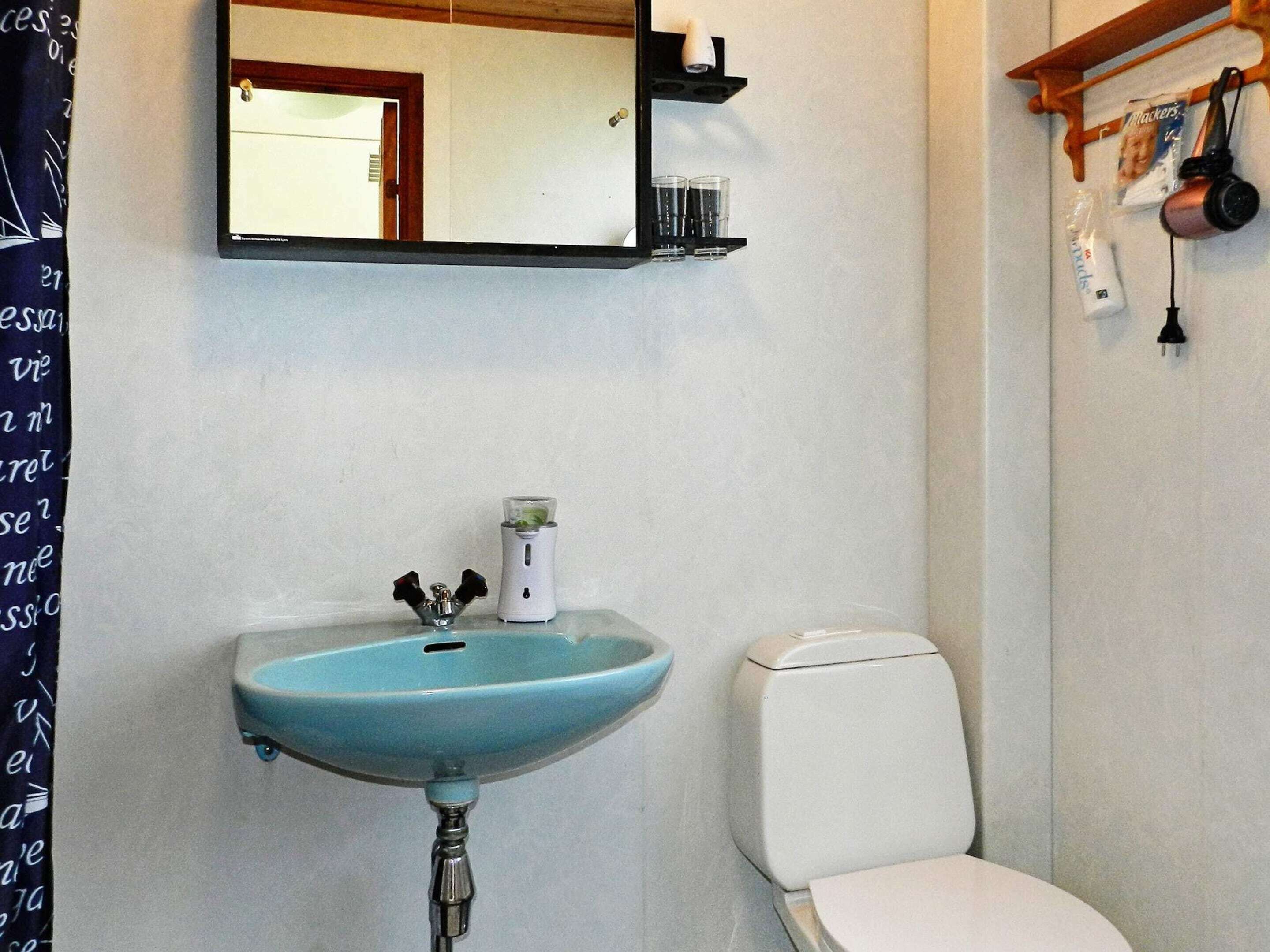 Un baño con un lavabo azul, un inodoro blanco y un espejo sobre el lavabo.