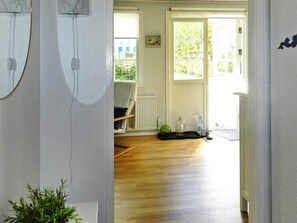 Une pièce avec un plancher en bois, une chaise, un radiateur et une porte donnant sur l’extérieur.