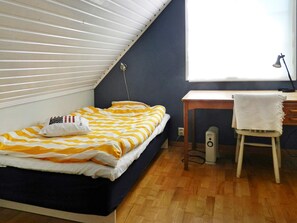 A bedroom with a bed, a desk, a chair, and a window.