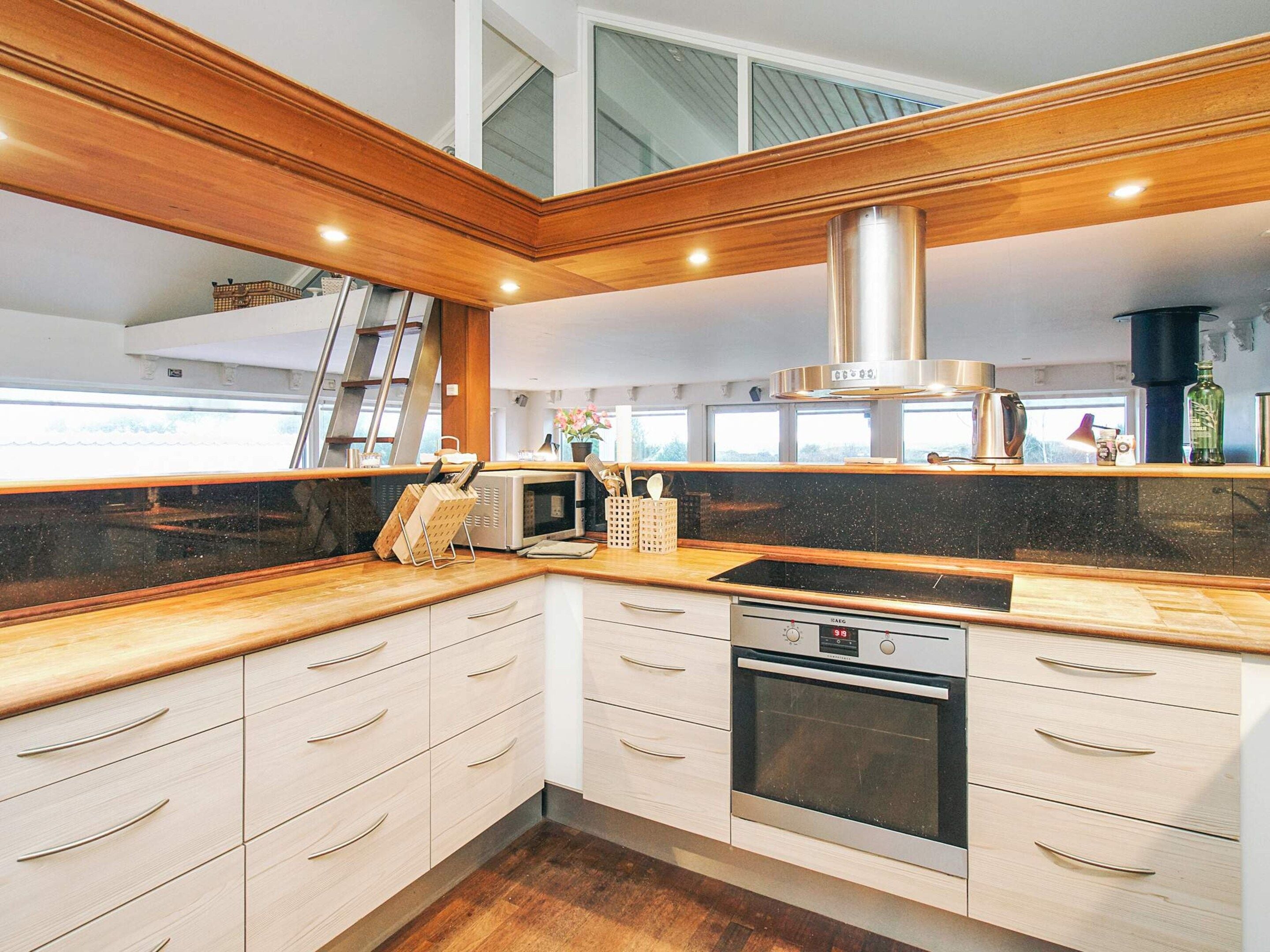 A modern kitchen with wooden cabinetry, a stainless steel range hood, and a built-in oven.