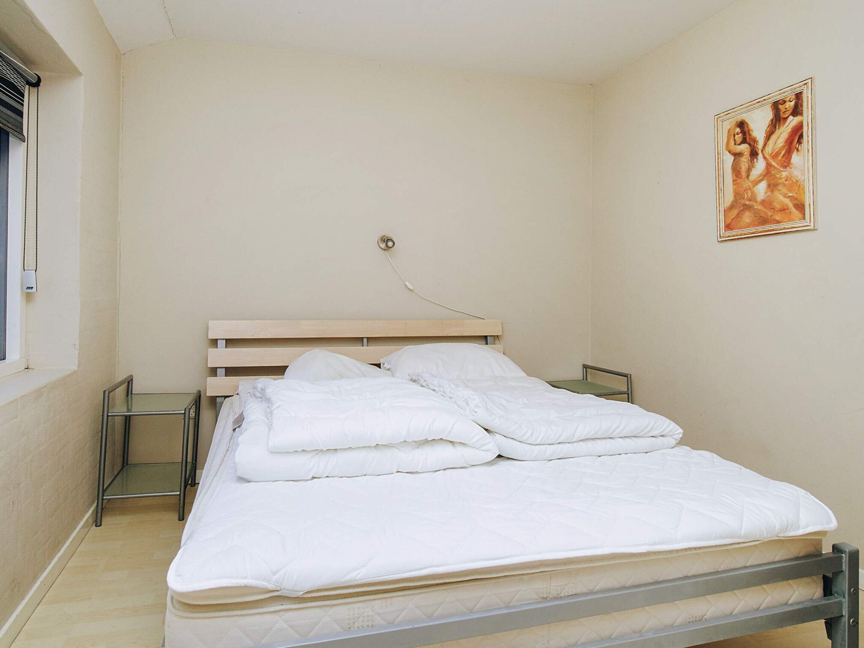 Een slaapkamer met een bed, een nachtkastje en een wandcontactdoos.