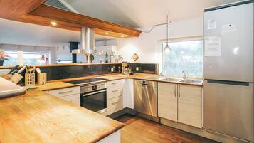 A modern kitchen with stainless steel appliances, wooden countertops, and a large window.