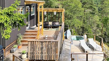 A wooden deck with outdoor seating and a hot tub.