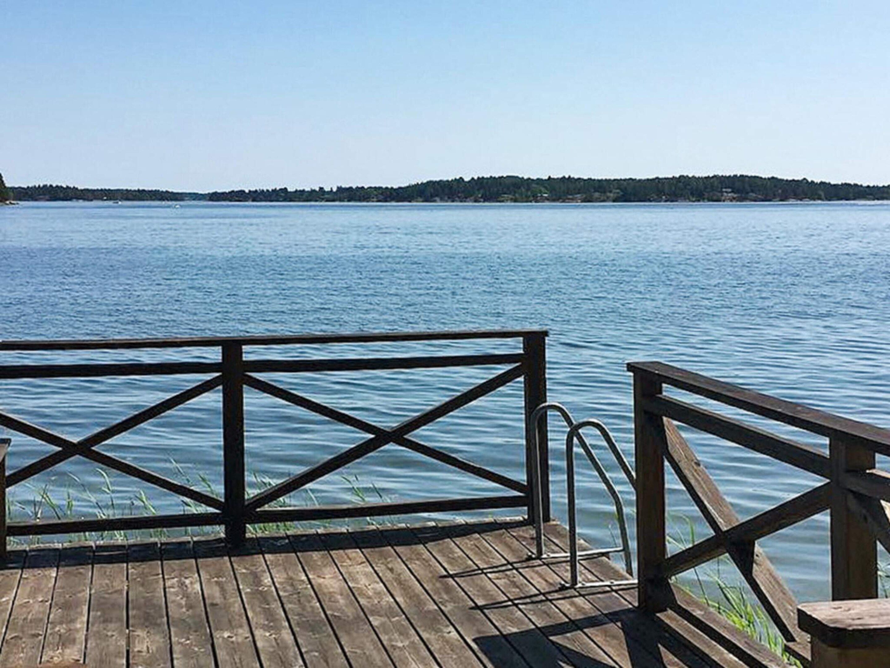 A wooden dock extending over calm water with a clear view of a distant shoreline.