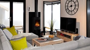 Uma sala de estar moderna com lareira, sofá, mesa de centro e televisão.