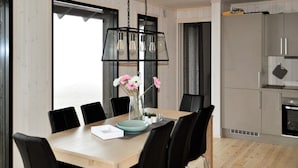 Uma sala de jantar moderna com mesa de madeira, cadeiras pretas e luminária pendente preta.