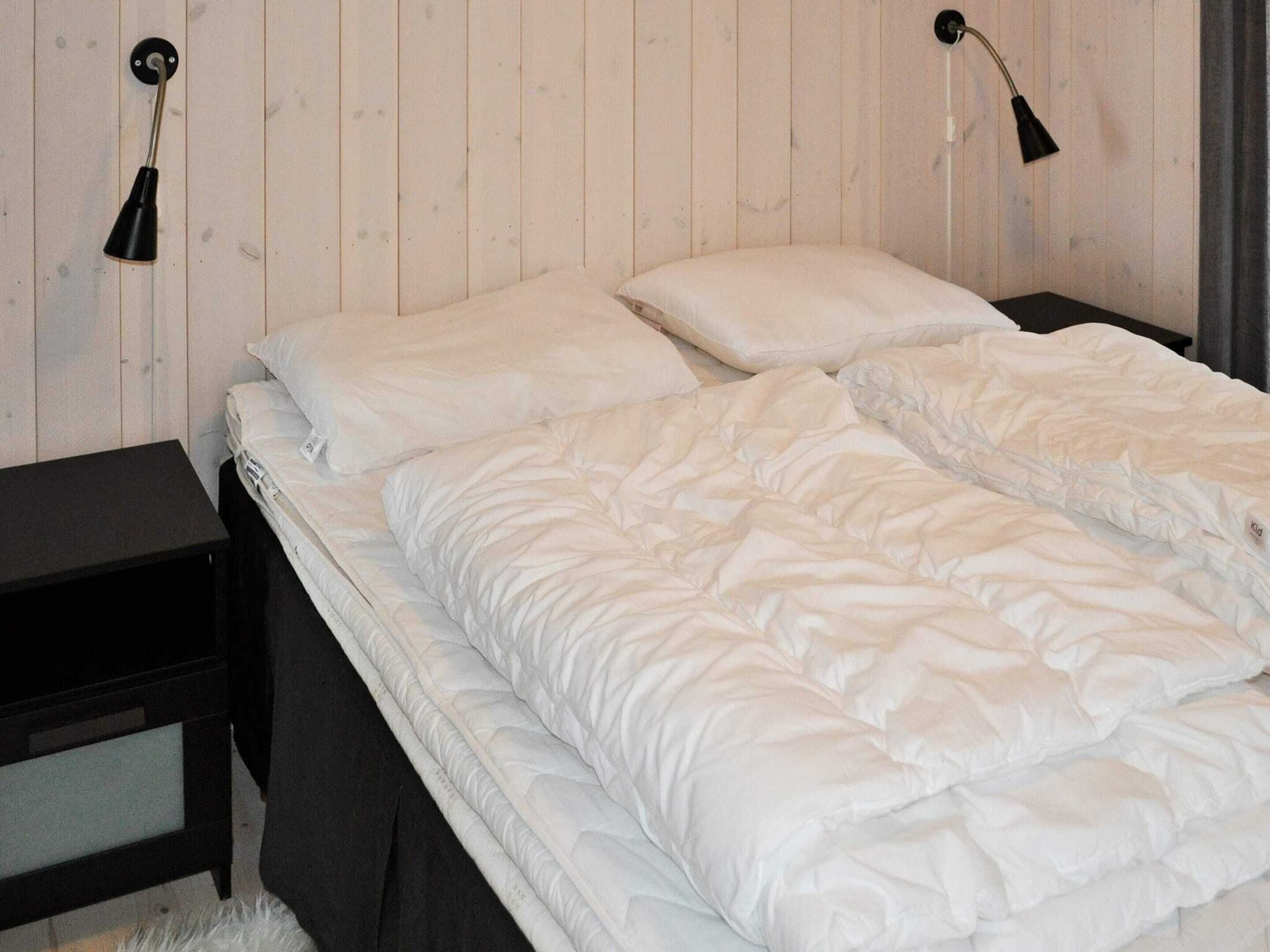 Una camera da letto con un letto, due comodini e una lampada a parete.