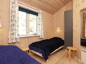 Une chambre avec deux lits, une fenêtre avec des rideaux, une lampe de chevet et un radiateur.