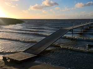 A wooden pier extending into the water with a bench at the end.