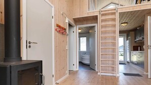 A wooden interior with a wood-burning stove, a kitchen area, and a bathroom visible through an open door. - 4 Star Holiday Home in Ulfborg (Ulfborg)