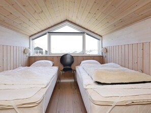 A room with two beds, a window, and a chair. - 4 Star Holiday Home in Ulfborg (Ulfborg)