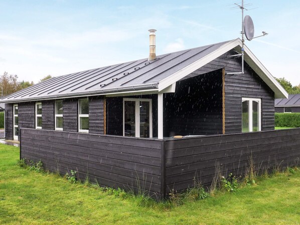 A single-story building with a dark exterior, a sloped roof, and a chimney.